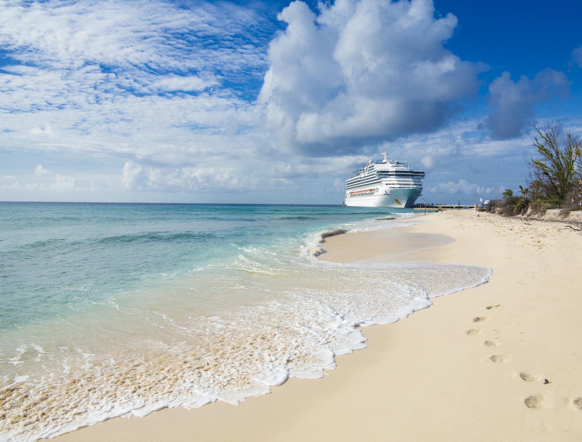 A cruise ship docks in Grand Turk with waves and sand in the for