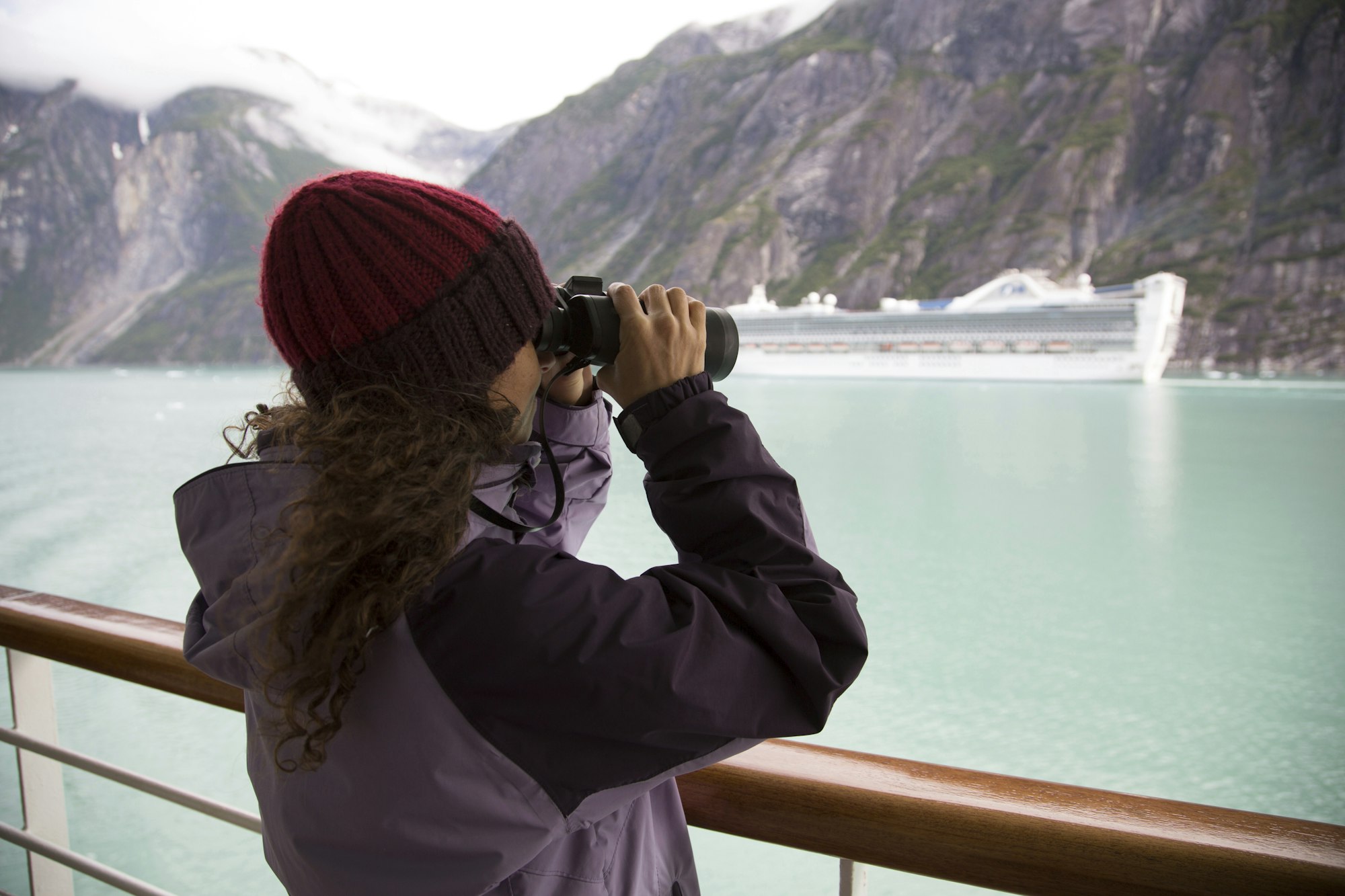 Woman using binoculars on cruise ship, Ketchikan, Alaska, USA