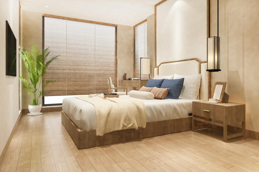 Serene modern bedroom at a Marriott hotel with light wood floors, neutral bedding, minimalist design, and warm ambient lantern lighting.