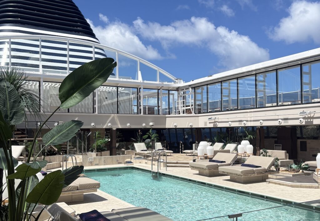 Luxury cruise ship pool area with comfortable sun loungers and a modern design, highlighting premium onboard amenities and relaxing ocean travel.