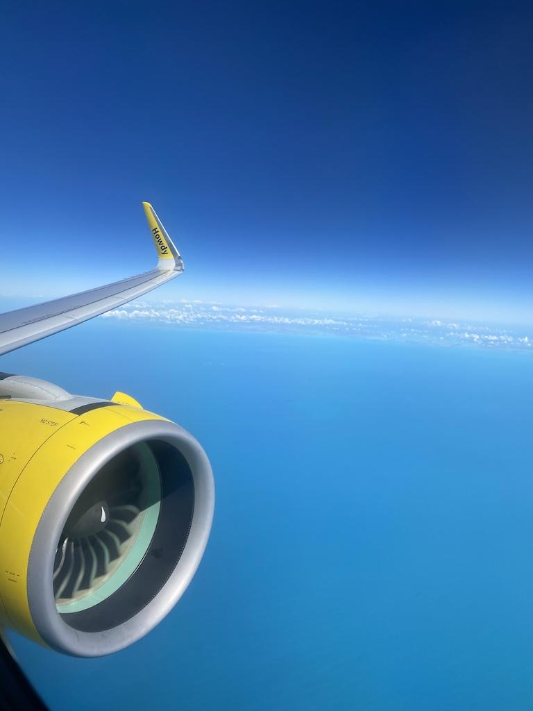 View of a bright yellow Spirit Airlines engine over the turquoise Caribbean sea, a common sight when flying to tropical destinations via the international airport.