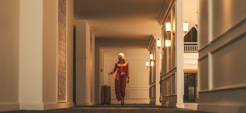 Woman in red walks through upscale hotel corridor, highlighting premium hotel rewards programs."