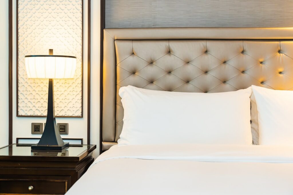 Luxurious private cabana or day bed area on a cruise ship or resort deck with white curtains, a canopy roof, and a serene view of the calm blue ocean and horizon.
