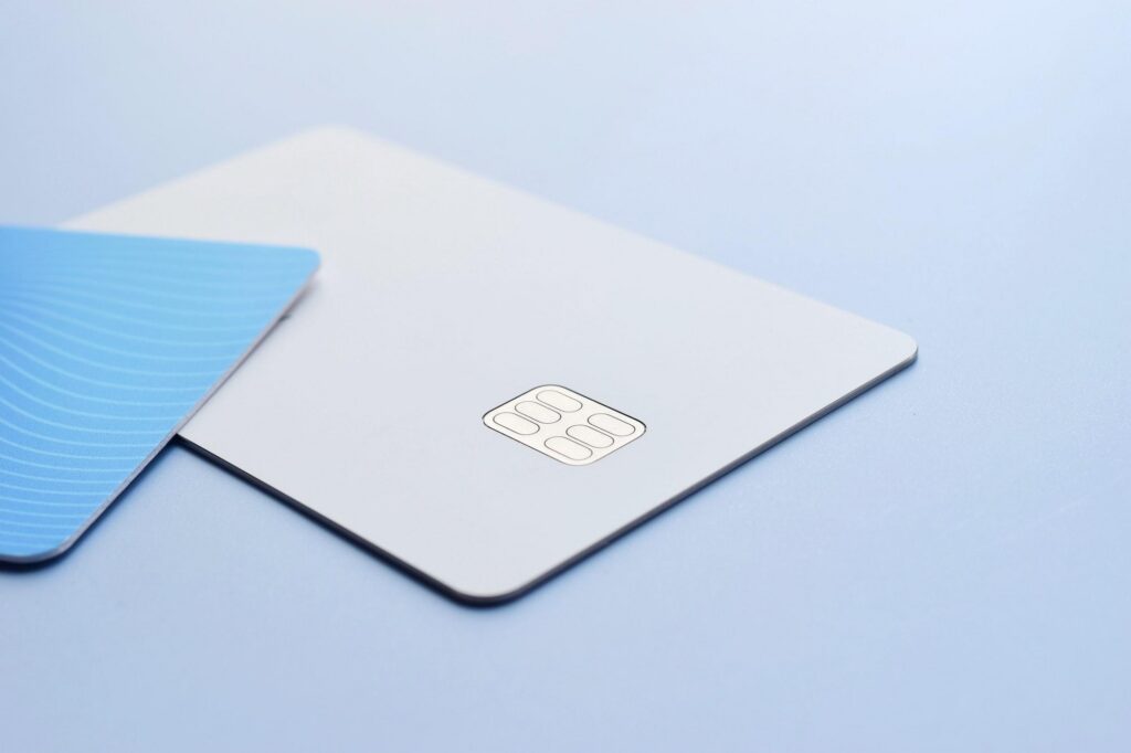 A white card with a metallic chip sits beside a blue patterned card, highlighting the secure technology of a Mastercard.
