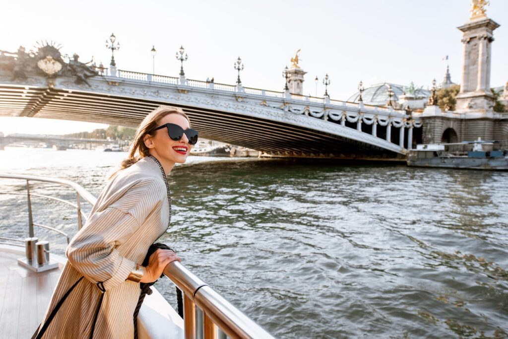 Woman in a bathrobe pouring champagne in a contemporary, luxury river cruise suite, highlighting the premium onboard experience.