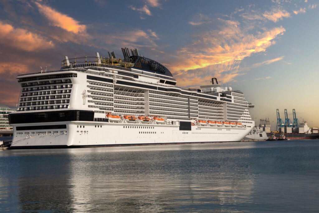 A large MSC Cruises vessel docked at a port during a golden sunset, showcasing its massive tiered balconies and modern architectural design. This premium ship provides a grand-scale vacation experience comparable to the top offerings of the Royal Caribbean cruise line, featuring world-class amenities and elegant exterior styling.