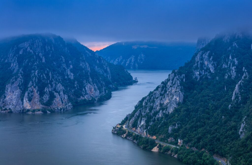 Modern river cruise ship sailing past lush green hills and historic hillside villages, showcasing one of Europe’s best river cruises.