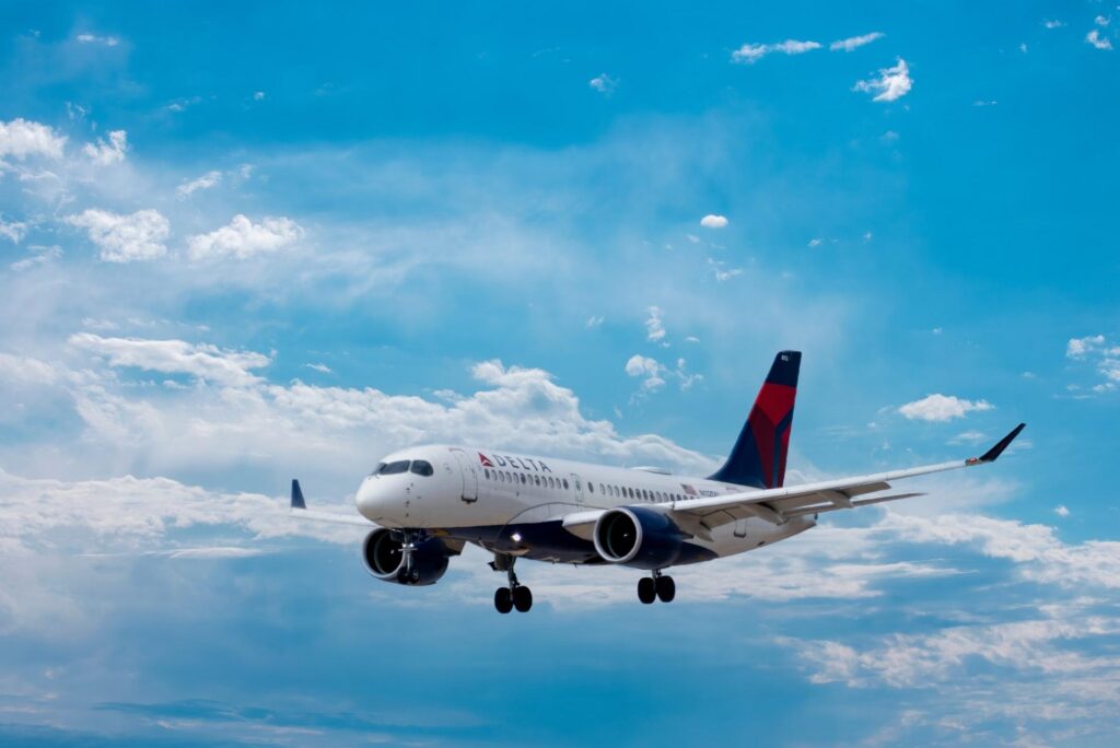 A commercial airliner descends through a bright blue sky, illustrating the fast-paced nature of modern aviation often contrasted with the exclusivity of private jet travel.