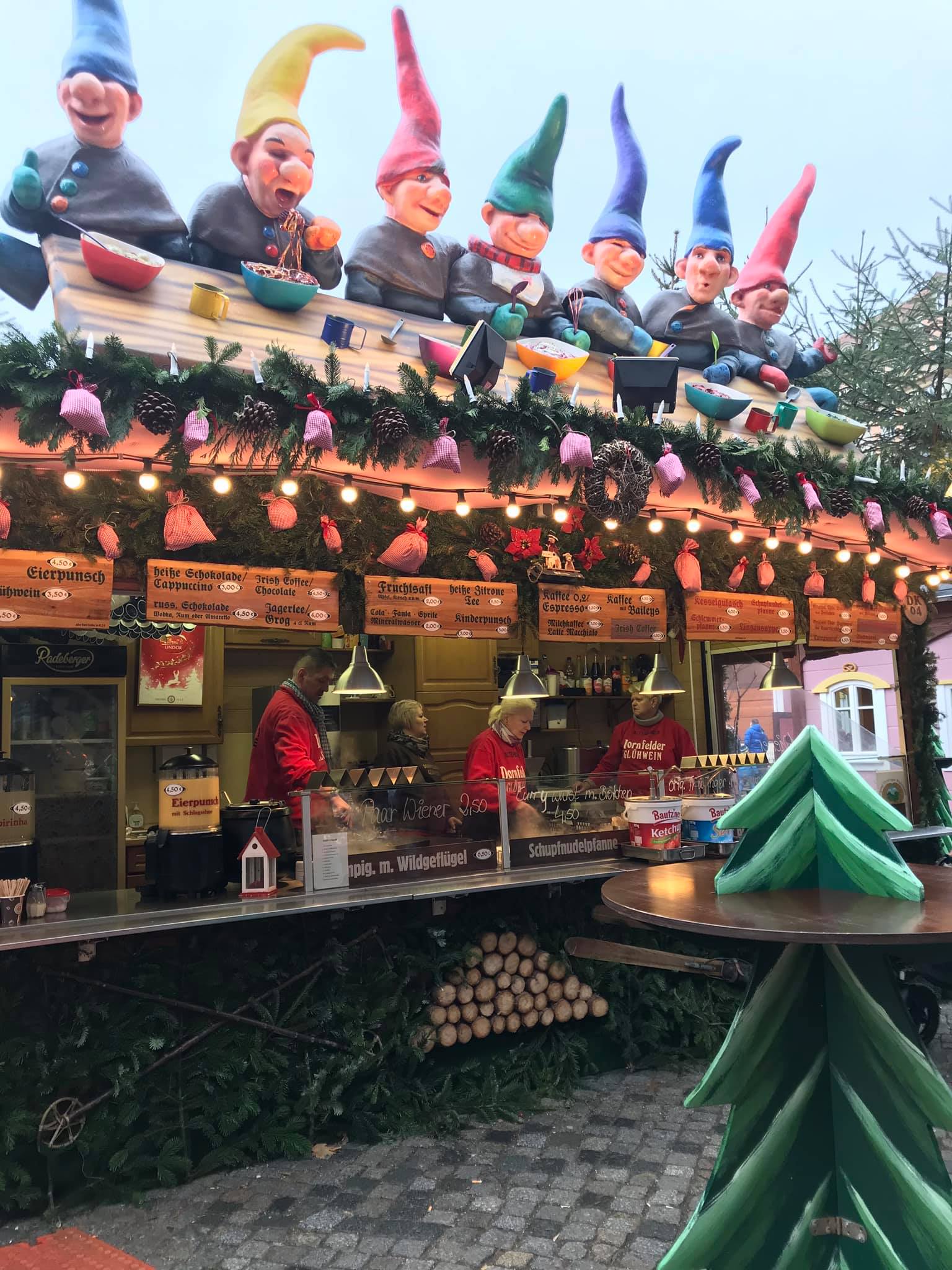 Traditional food stall with festive gnome decorations and pine garlands, a staple sight at authentic German Christmas markets.