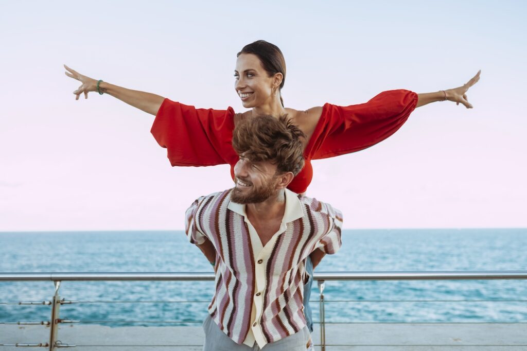 A couple in a romantic pose on a cruise ship with the ocean in the background.