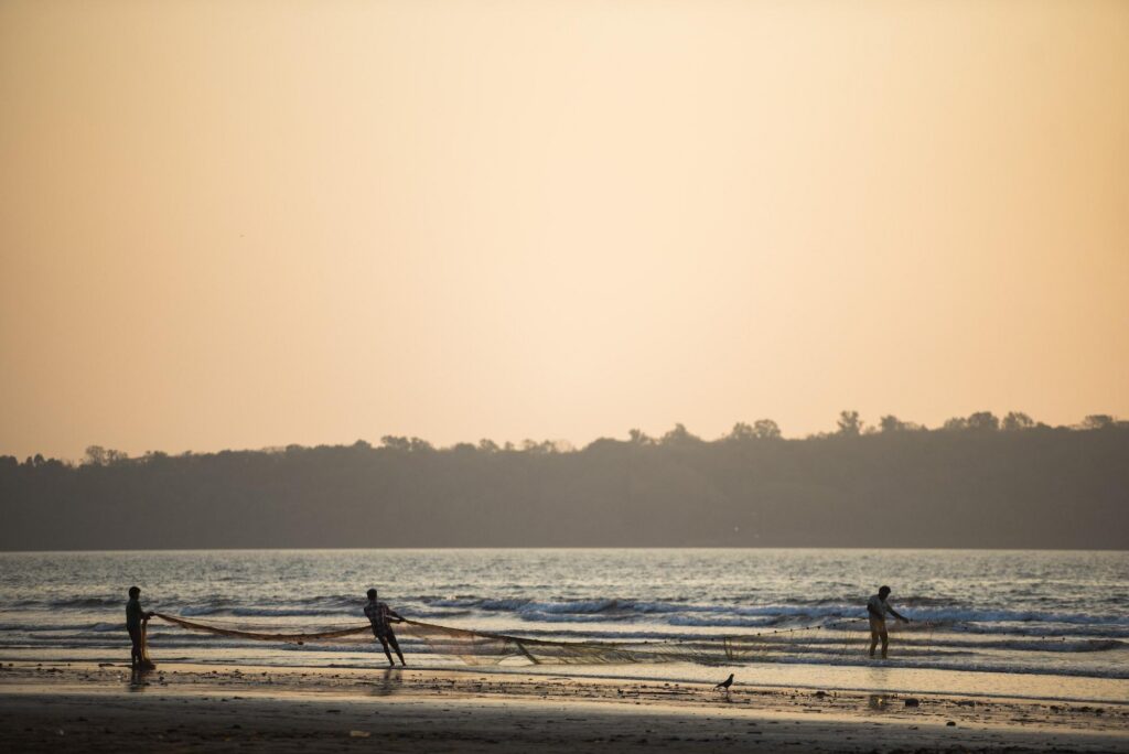 Fishermen pull in large nets from the ocean waves at sunset near the location of a Miramar beach bar.