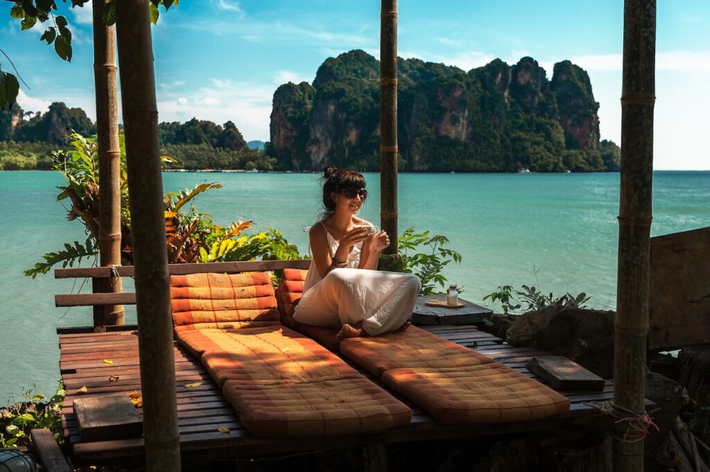 Guest relaxing in a secluded, open-air luxury bungalow with a stunning view of turquoise water and limestone karsts, symbolizing a hidden gem resort.
