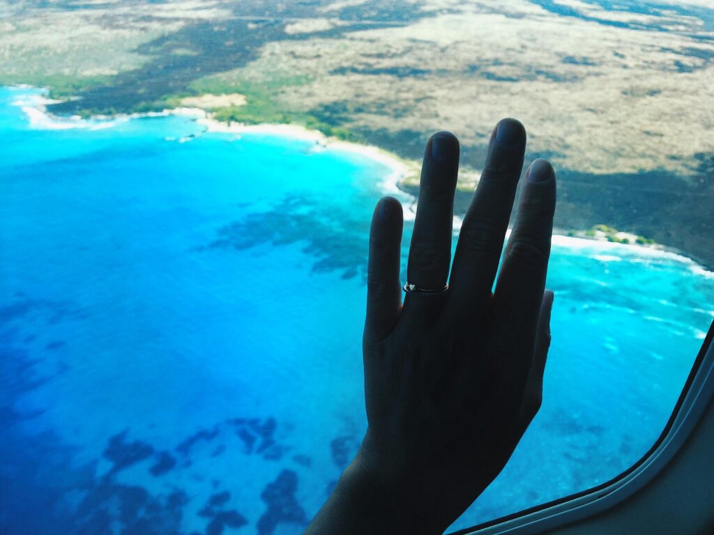 Aerial view from a plane window over clouds and ocean ensuring safe flights.