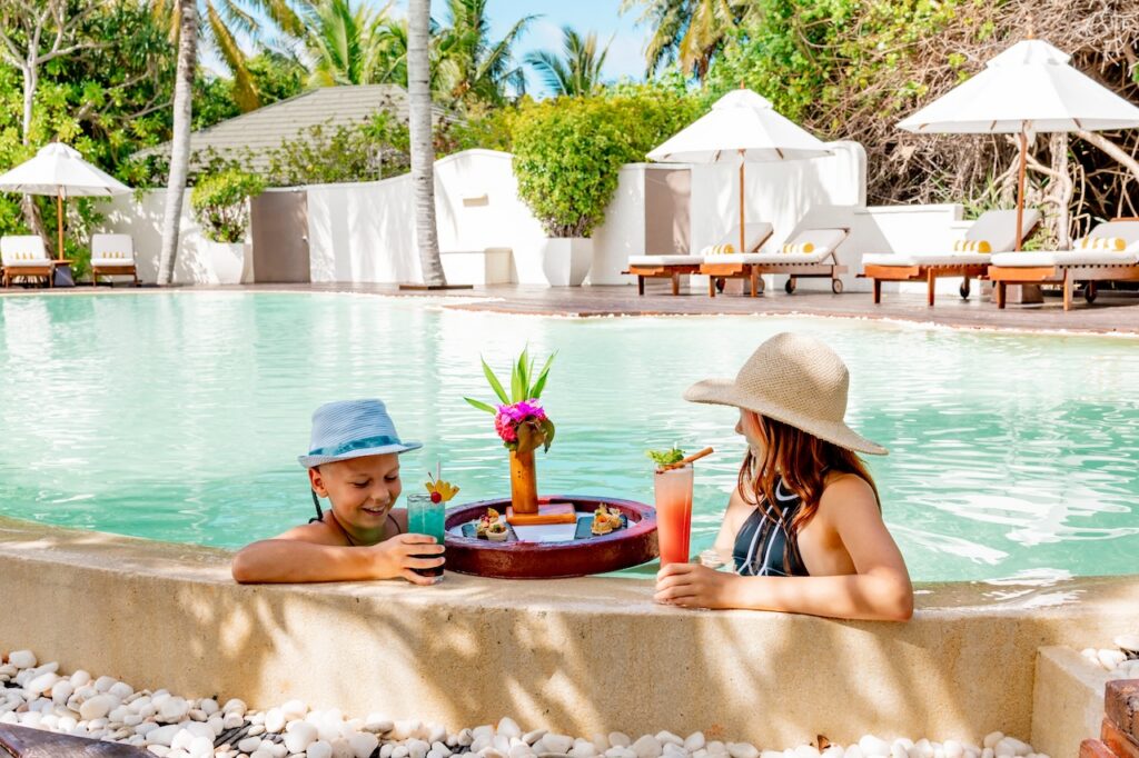 Two guests relaxing on sun loungers by a pristine pool, reflecting the luxurious and comfortable resort amenities.