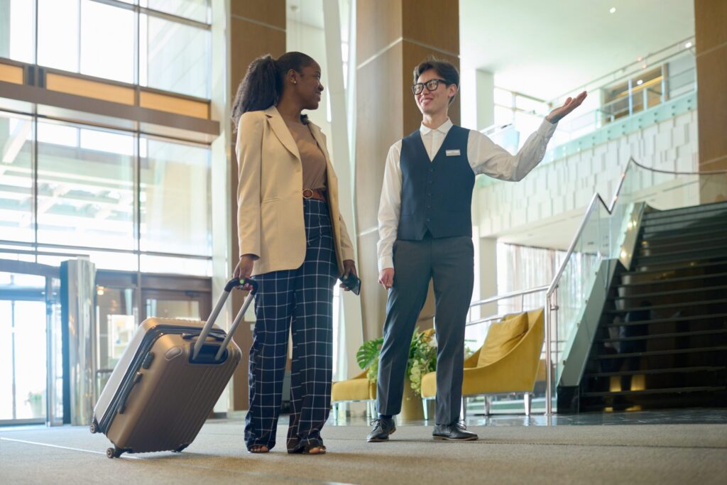 Hotel concierge guiding a guest with luggage in a luxury hotel lobby, illustrating Hyatt Privé exclusive travel benefits.