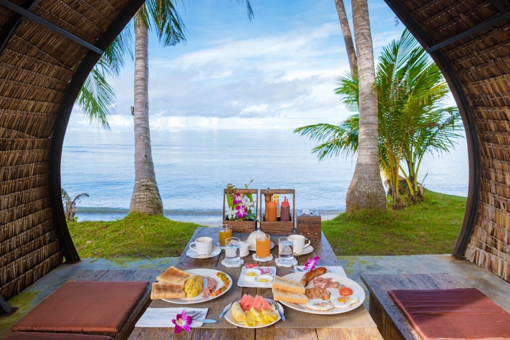 Gourmet breakfast served in a private, open-air cabana overlooking the ocean, highlighting the personalized dining and intimate setting of a small boutique island resort.