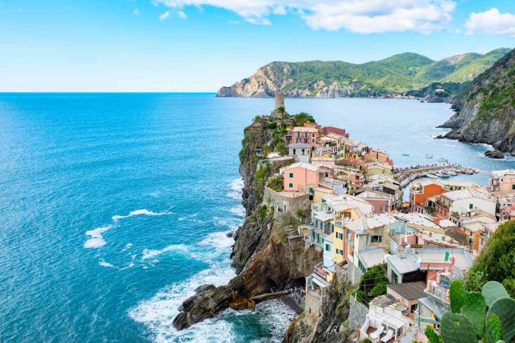 Colorful village built into steep cliffs overlooking the turquoise Mediterranean Sea, representing a scenic stop on a luxury Silversea Italy cruise.