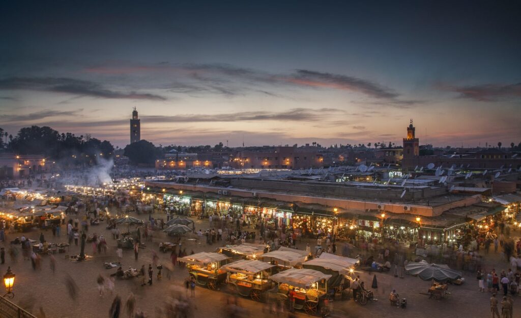 Horse-drawn carriages by historic red walls reflecting the history of Marrakesh.