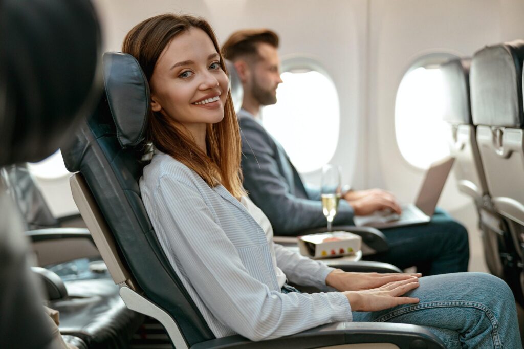 Joyful woman sitting in passenger chair in airplane.
