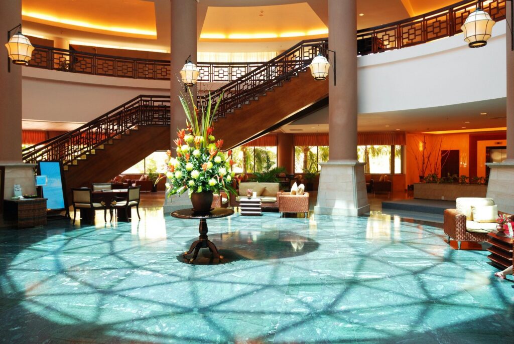Sunlit luxury resort lobby with teal marble floors, wooden staircase, and floral centerpiece featured in Exploring Marriott Stars.