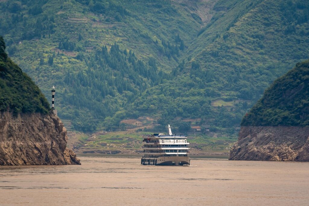 Scenic luxury river cruise ship navigating a lush mountain gorge.