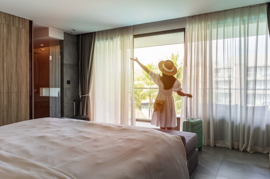 Woman checking into a modern, luxurious hotel room with a tropical view, ideal for highlighting premium vacation accommodations and travel comfort.