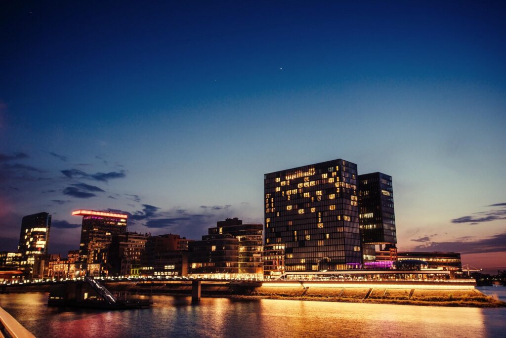 A glowing city skyline at twilight reflected in the water, featuring luxury accommodations often available through Hyatt Prive.