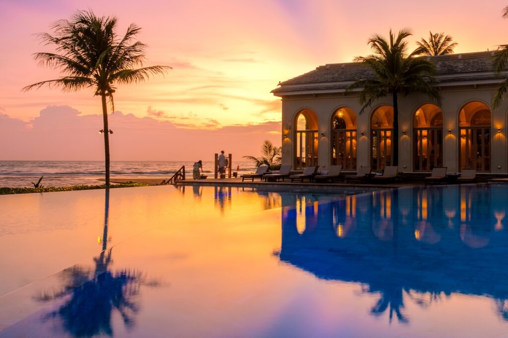 Luxury resort infinity pool at sunset with a beachfront view, highlighting the perfect tropical setting for a serene and exclusive vacation.