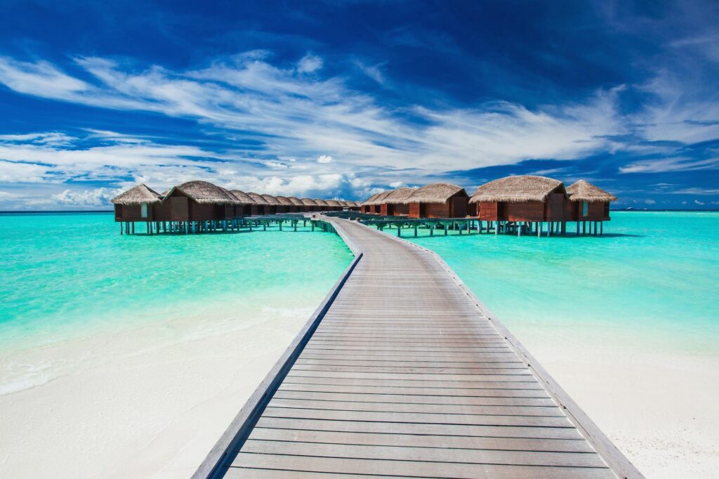 Luxury overwater bungalows and villas extending into a turquoise lagoon, offering an exclusive escape at a private island resort.
