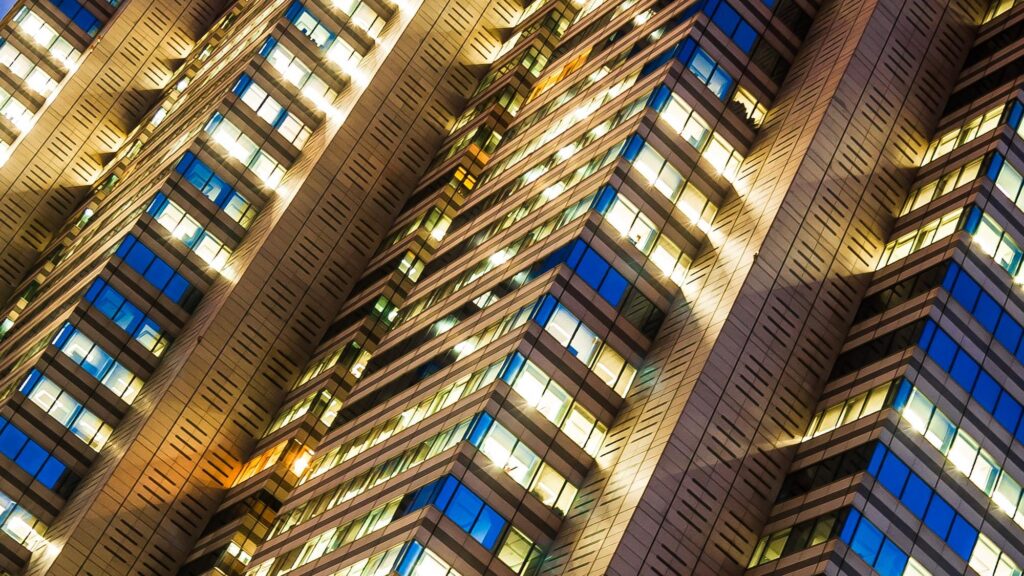 Modern luxury hotel exterior at night with illuminated windows, representing premium travel experiences and Hyatt Prive Benefits.