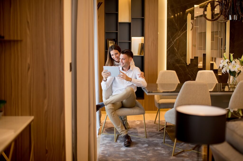 A couple relaxing in a sleek, luxurious hotel suite, illustrating the benefit of the complimentary room upgrade perk achieved through Hyatt Privé.