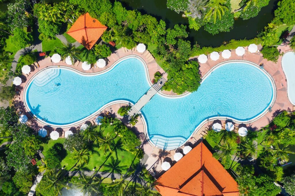 Aerial view of a luxury all-inclusive British Virgin Islands resort with a stunning pool and thatched huts, perfect for an adults-only beach escape.