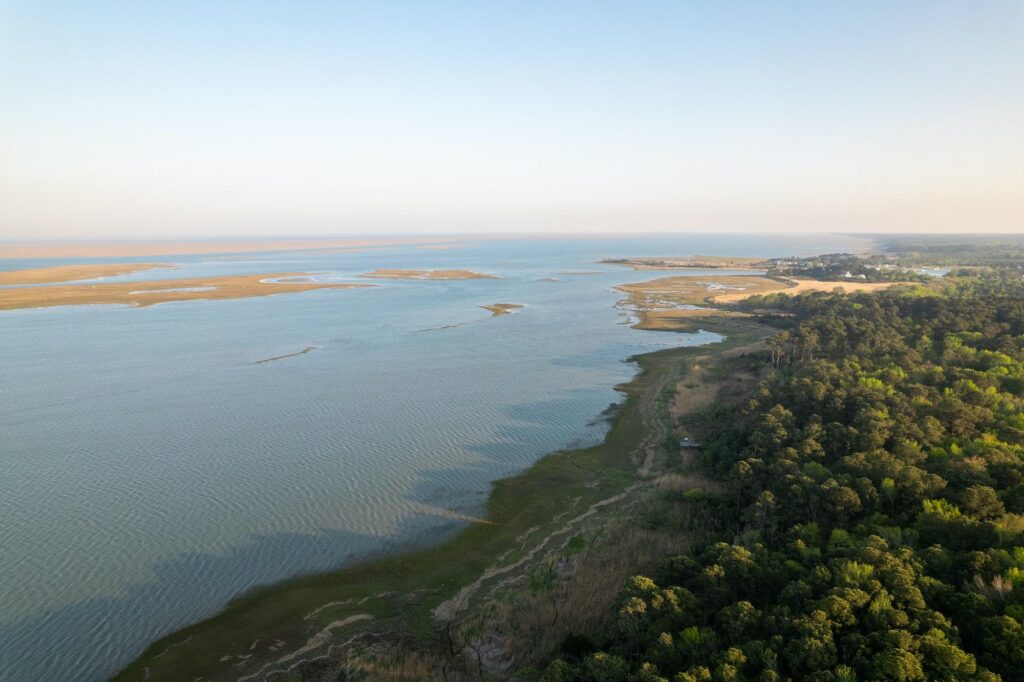 A stunning aerial view of the coastline showing the proximity of the ocean to lush greenery and upscale hotels in Virginia Beach.