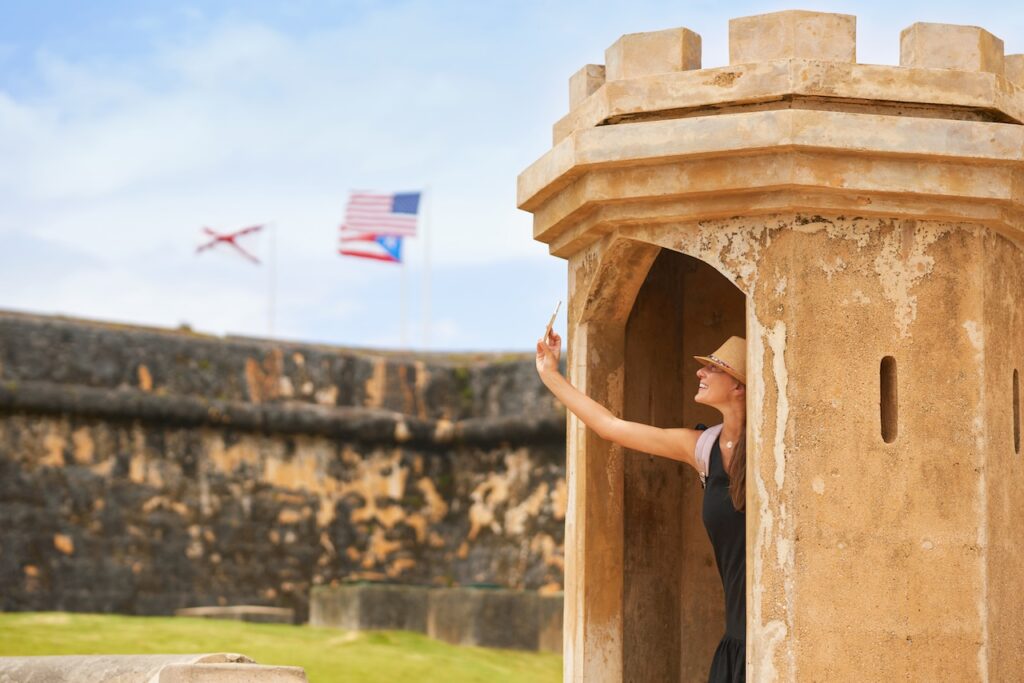 Woman taking a selfie at a historic garita in Old San Juan, Puerto Rico, highlighting the rich history and adventure for a family or cultural trip.