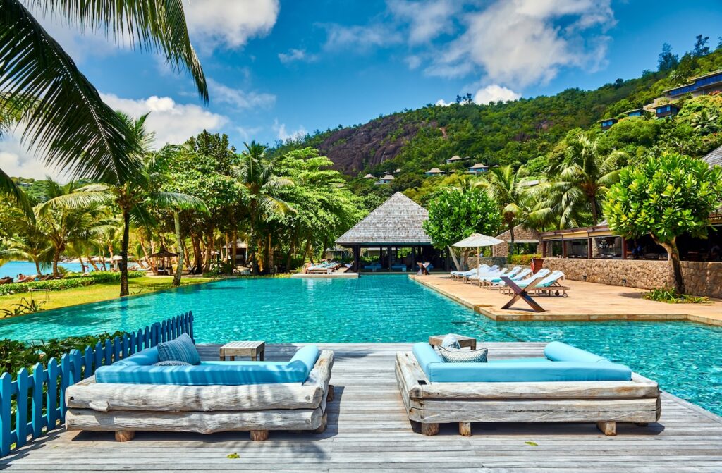 Aerial view of an exclusive luxury island resort with private villas and pools, showcasing a stunning, high-end destination accessible via direct U.S. flights.