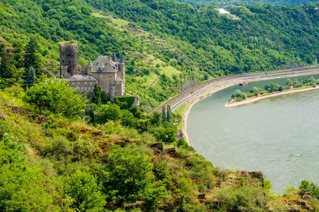 Historic castle nestled in lush green hills overlooking a European river, representing a charming, scenic stop on a short river cruise.