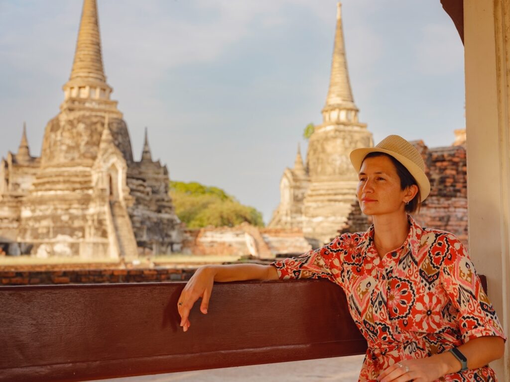 Solo traveler enjoying the serene atmosphere while standing among ancient Thai temple ruins, highlighting the safe and independent cultural exploration available.