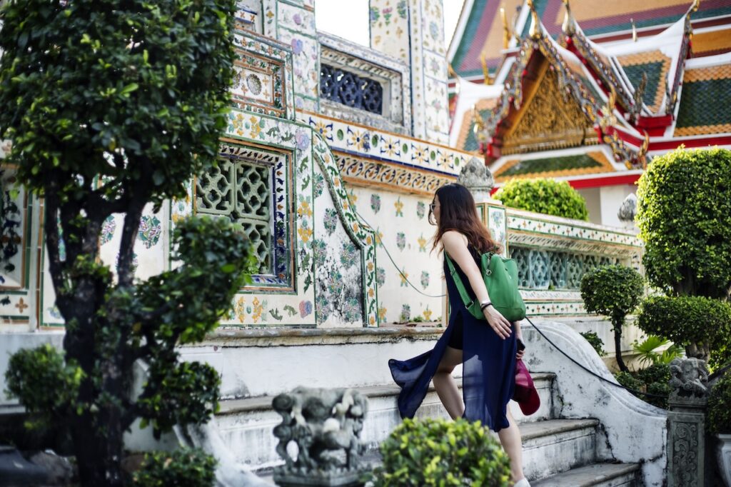 Traveler walking up stairs at an ornate, beautiful Thai temple, representing the essential cultural exploration included in a luxury getaway guide.