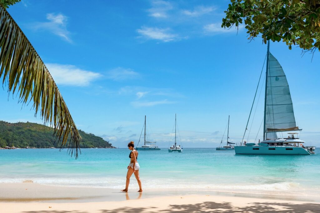 Relaxing on a pristine beach with catamarans nearby, highlighting sailing and sunbathing as top luxury activities to do in Saint Barthélemy.