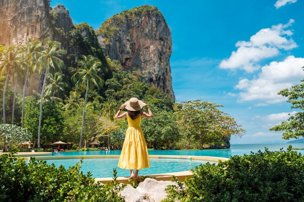 Traveler standing at a stunning infinity pool overlooking the ocean, symbolizing the perfect dream escape and luxurious resort setting in Thailand.