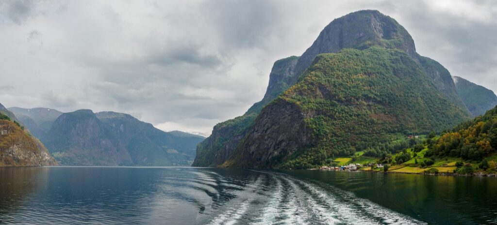 A scenic view of a river surrounded by towering green mountains with a river cruise experience rich cultural heritage, showcasing the natural beauty and historic landscape of Europe.