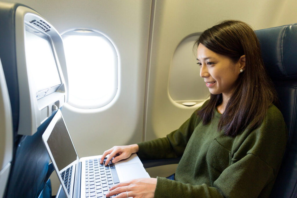 A passenger using a laptop on a fold-down tray table during a United Airlines flight.