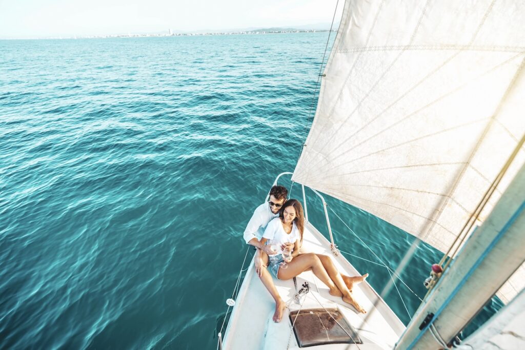 Couple sitting on the deck of a sailboat on the turquoise sea, highlighting a luxury yacht or sailing excursion on the Saint Barthélemy one-day itinerary.