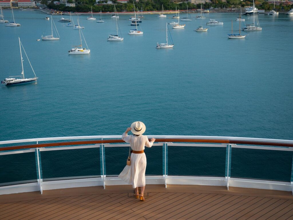 An elegant evening social gathering on the deck of a celebrity cruises ship, where guests in formal attire enjoy cocktails and conversation as the sun sets over the ocean.