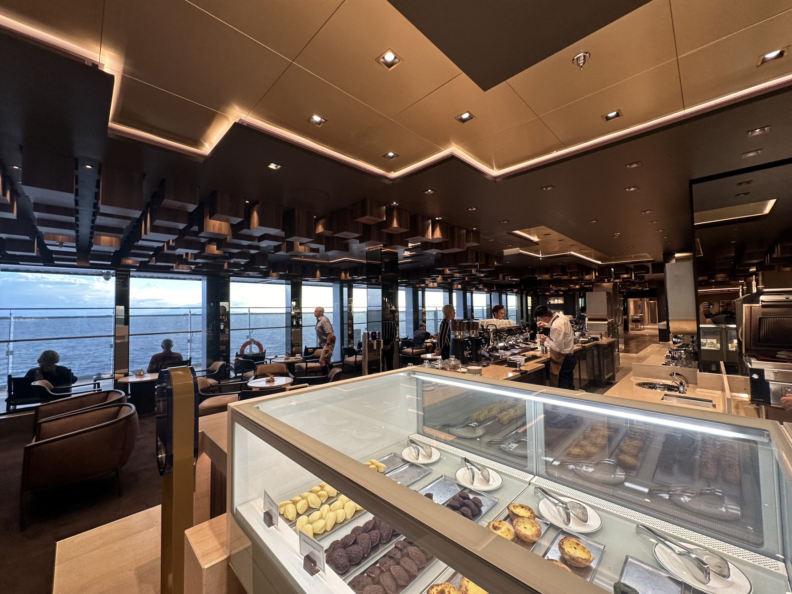 Pastry case and espresso bar at Crema Café aboard Explora Journeys, with ocean views